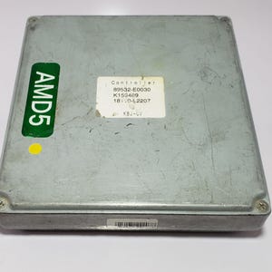 以下が含まれることがあります： 「AMD5」と書かれた緑色のステッカーが付いた、長方形の灰色の電子コントローラー。 「Controller」や数字を含むテキストが表示された白いステッカー。 コントローラーにはバーコードがあり、ネジで固定されています。