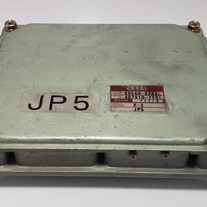 以下が含まれることがあります： 四角い銀色の電子制御ユニット（ECU）で、各コーナーにネジが見えます。「JP5」や「ZEXEL」などの文字と数字が記載されたラベルが付いています。ECUは、自動車や産業用途で使用される可能性が高いです。