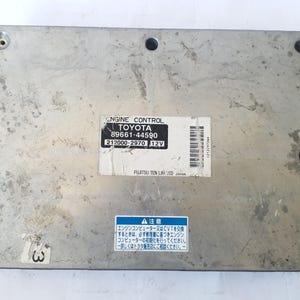 May include: A silver Toyota engine control module, featuring the text "ENGINE CONTROL" and "TOYOTA". The module has a sticker with the numbers "89661-44590" and "212000-2970 12V". A blue sticker with Japanese text is also visible.