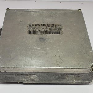 Puede incluir: Una unidad de control electrónico (ECU) de color plateado con forma rectangular. La ECU tiene una etiqueta con texto y un código de barras. La unidad está hecha de metal y tiene una superficie texturizada. La etiqueta incluye el texto "BOSCH" y otra información técnica.