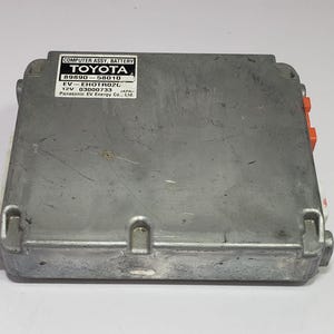 以下が含まれることがあります： シルバーカラーのトヨタ製コンピューターアセンブリバッテリー。ラベルにはモデル情報とともに「COMPUTER ASSY、BATTERY TOYOTA」と記載されています。オレンジ色のコネクタが側面にあります。長方形のアイテムです。
