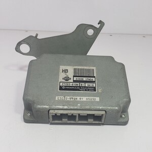 May include: A grey automotive electronic control unit (ECU) with the text "NISSAN" and "Hitachi, Ltd. Tokyo Japan MADE IN JAPAN". The ECU has a connector and mounting bracket.