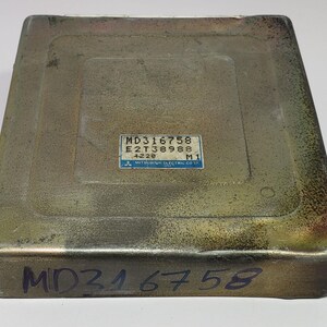 May include: A gold-coloured metal box with the text "MD316758 E2T38988 4228 M1" and "MITSUBISHI ELECTRIC CORP." printed on a blue label. The box also has the text "MD316758" written in black on the bottom.