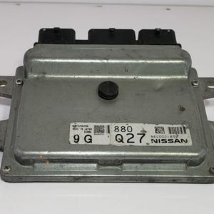 May include: A silver electronic control unit (ECU) with black connectors. The ECU is rectangular with mounting tabs and a label that reads "NISSAN". The label also includes the text "880 Q27".