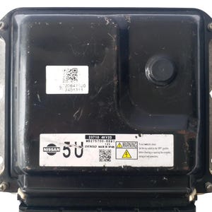 以下が含まれることがあります： 日産のロゴと「5U」の番号が付いた黒色の電子制御ユニット（ECU）。 ECUには、「23710 4KV2D」や警告記号など、テキストとQRコードが記載されたラベルがいくつかあります。 このユニットは12Vシステム用に設計されています。