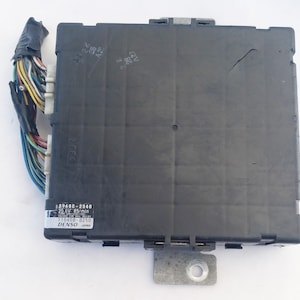 Peut inclure: Unité de contrôle électronique noire avec un support métallique. Un faisceau de fils multicolores est attaché sur le côté. L'unité contient du texte, dont "89680-2040" et "DENSO JAPAN".