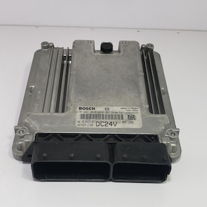Puede incluir: Una unidad de control electrónico (ECU) de color plateado con conectores negros. La unidad rectangular presenta aletas de refrigeración y una etiqueta con la marca "BOSCH" y el texto "DC24V".