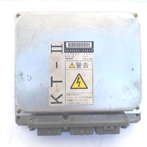 Könnte beinhalten: Ein silbernes Kfz-Steuergerät mit der Aufschrift "KT-II" und Warnsymbolen. Das Modul hat mehrere Anschlüsse und den Text "DENSO" und "MADE IN JAPAN".