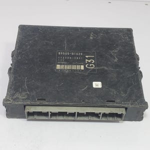 Puede incluir: Una unidad de control electrónico automotriz rectangular de color negro con un puerto de conector gris en la parte frontal. La superficie superior muestra el texto 89560-B1620, 112300-3831, 12V, DENSO y G31, junto a un código de barras y un código QR.