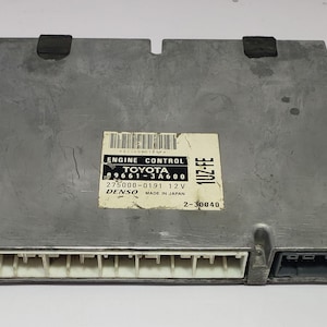 以下が含まれることがあります： 「ENGINE CONTROL TOYOTA 1UZ-FE 275000-0191 12V DENSO MADE IN JAPAN 2-30040」と印刷された灰色のトヨタエンジンコントロールユニット。