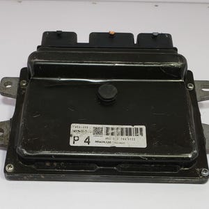 May include: Black electronic control unit, rectangular with connectors and mounting brackets. A label with text and a barcode is on the front. Likely for automotive use. Dimensions are approximately 20 cm x 15 cm.