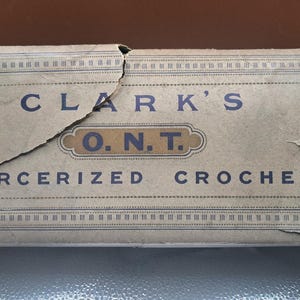 May include: A vintage box of Clark's O.N.T. Mercerized Crochet thread. The box is made of cardboard and has a blue and white label with the company's name and product information.