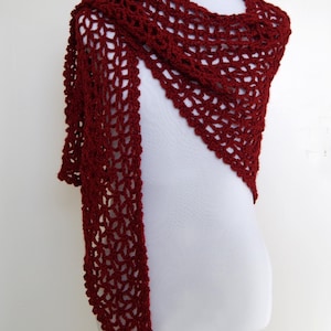 May include: A maroon crocheted shawl with a delicate openwork pattern. The shawl is draped over a white mannequin.