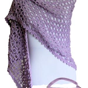 May include: A lavender crocheted shawl and matching handbag. The shawl is a triangular shape with a delicate openwork pattern. The handbag has a flap closure and a single strap.