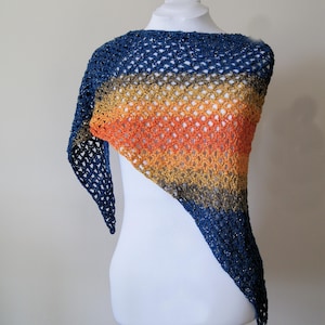 Könnte beinhalten: Ein dreieckiger Häkel-Schal mit einem Farbverlauf von Blau, Gold, Orange und Rot. Der Schal ist mit einem zarten Lochmuster gearbeitet und hat einen dezenten Schimmer.