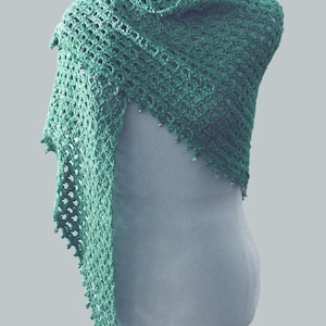 May include: A green crocheted shawl with a lacy pattern. The shawl is draped over a mannequin.