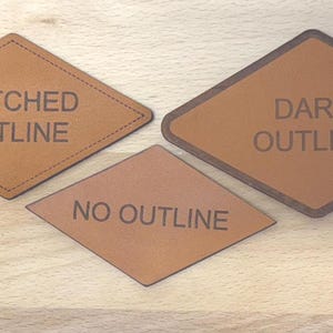 May include: Three diamond-shaped tan leather patches. The top left patch features a stitched border and the text STITCHED OUTLINE. The top right patch has a dark brown border and the text DARK OUTLINE. The bottom patch has no border and the text NO OUTLINE.