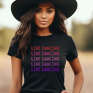 May include: A black t-shirt with the text "LINE DANCING" repeated five times in a gradient of red, pink, and purple.