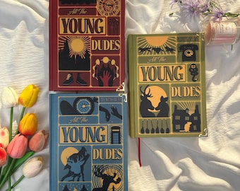 May include: Three hardcover books titled All The Young Dudes by Ms King Bean. The red, green, and blue covers feature gold-toned corner protectors and intricate graphic illustrations including silhouettes of animals, buildings, and various objects.