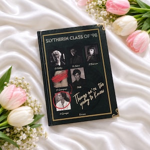 May include: A black hardcover book titled Slytherin Class of '98: Things we're too young to know. The cover features gold-toned corner accents and a grid of black-and-white portraits with names, including a red-crossed image and a circled portrait.