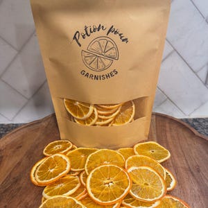 May include: A brown paper bag with the text "Potion Power Garnishes" and a lemon slice graphic. The bag is filled with dried orange slices.