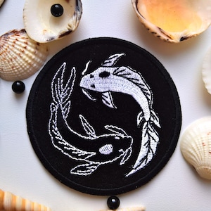 Puede incluir: Parche de tela negro con un símbolo yin yang bordado en blanco con dos peces koi, uno blanco y otro negro.