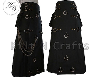 Könnte beinhalten: Schwarzer Kilt mit mehreren Reihen silberner und goldener Beschläge, darunter Ringe und Nieten. Der Kilt hat ein Kettendetail, das an der Vorderseite hängt.