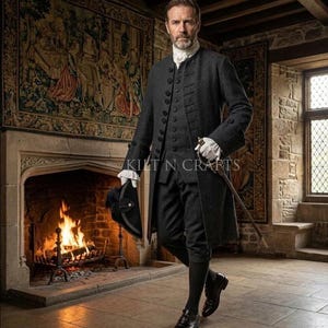 May include: A dark gray, three-piece suit with a long coat, vest, and breeches. The suit features decorative buttons and is paired with a white collared shirt, gloves, and black shoes. A black hat with a feather and a sword are also visible.