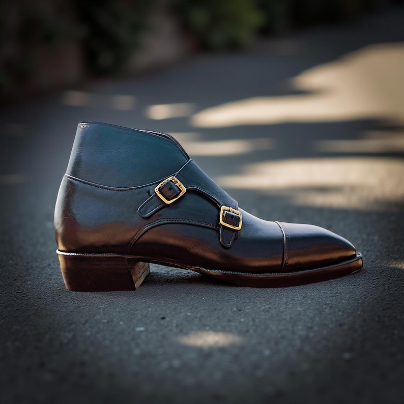 Pu&ograve; includere: Stivaletto in pelle nera con punta e due chiusure con fibbia color oro. Lo stivaletto ha un tacco basso e un aspetto lucido. La calzatura &egrave; progettata per un look sofisticato.