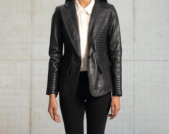 May include: A black leather blazer with a notched lapel, two front pockets, and a single-button closure. The blazer features quilted detailing on the shoulders and sleeves. The model is wearing a white collared shirt and black pants.