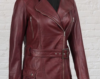 May include: A burgundy leather jacket with a notched collar, asymmetrical zipper, and a belted waist. The jacket features multiple zippered pockets and a flap pocket. The sleeves are long, and the jacket is displayed against a white brick wall.