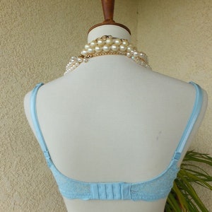 May include: A light blue lace bra with adjustable straps and a hook and eye fastening at the back.