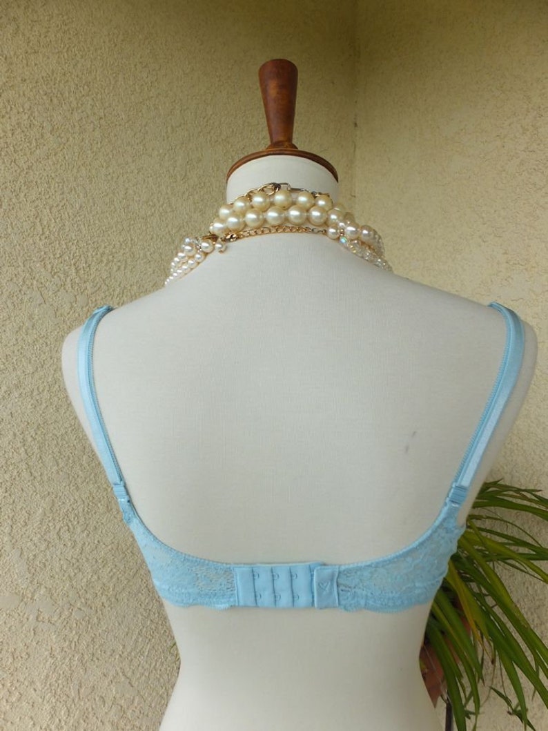 May include: A light blue lace bra with adjustable straps and a hook and eye fastening at the back.
