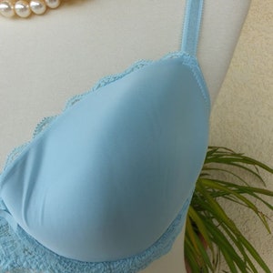 May include: A light blue bra with lace trim. The bra has adjustable straps and a smooth, seamless cup.
