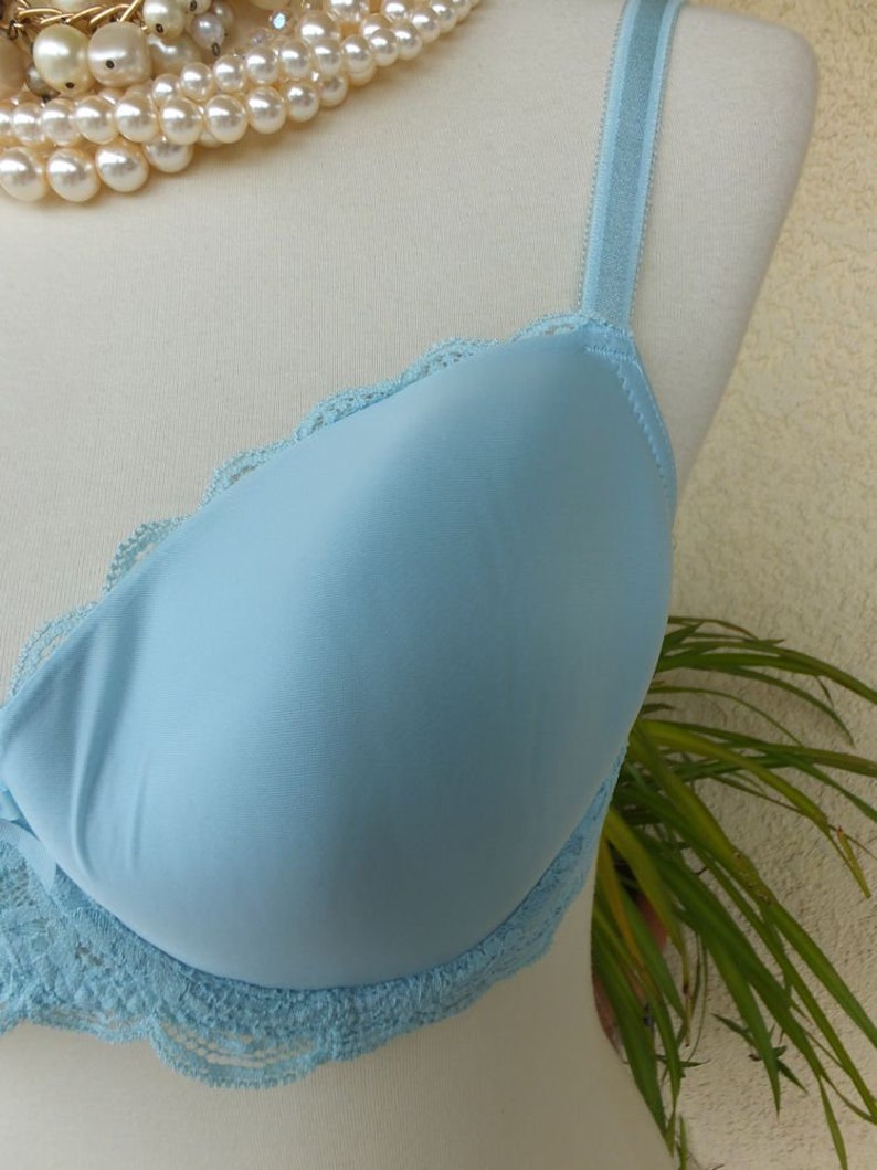 May include: A light blue bra with lace trim. The bra has adjustable straps and a smooth, seamless cup.