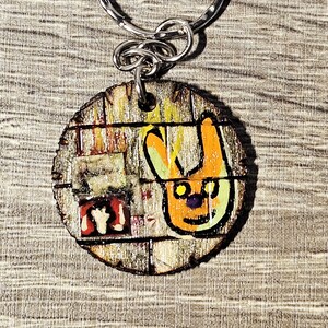 Llavero de madera decorado con pirograbado – Muro urbano, pegatinas rasgadas y conejo estilizado – Pieza única