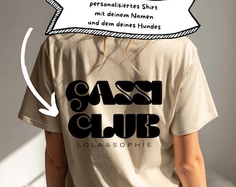 May include: Beige t-shirt with the words "GASSI CLUB" in large, black, retro-style font. Below the text are the names "LOLA & SOPHIE". A banner above the text reads "personalisiertes Shirt mit deinem Namen und dem deines Hundes".
