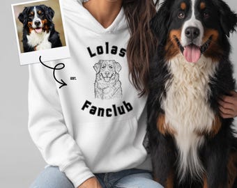 May include: White hoodie with the text "Lolas Fanclub" and a dog illustration. A photo of a Bernese Mountain Dog is on the left. A Bernese Mountain Dog is sitting next to the person wearing the hoodie.