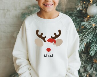 May include: A white sweatshirt featuring a reindeer face design with brown antlers, tan ears, a red nose, and a Santa hat. The name "Lilli" is printed below the reindeer face in black. The sweatshirt is a festive holiday garment.