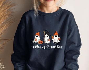 Könnte beinhalten: Marineblaues Sweatshirt mit drei Cartoon-Geistern, die orangefarbene Hüte tragen und einen Kürbis, einen Besen und eine Kaffeetasse halten. Der deutsche Text "süßes oder saures" ist darunter gedruckt. Getragen von einem Kind.
