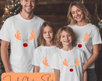 May include: A family of four wearing matching white t-shirts with reindeer antler designs. The shirts have orange antlers, a red nose, and the words "Dad", "Mom", and "Kid" printed on them. The image also has the text "Family Christmas Shirt".