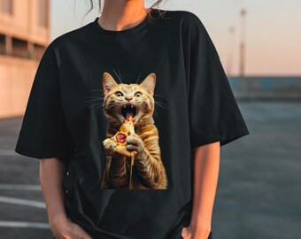 May include: Black t-shirt featuring a digitally rendered image of an orange tabby cat devouring a slice of pizza. The cat's mouth is wide open, and cheese is dripping from the pizza. The shirt is a casual, oversized style.