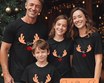 May include: Four people wearing matching black t-shirts with reindeer antler designs and the words "Dad", "Mom", "Mia", and "Chu". The shirts have an orange antler design with a red nose. The text "Family Christmas Shirt" is also visible.
