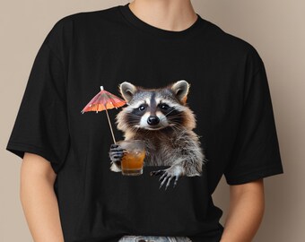 May include: Black t-shirt featuring a raccoon holding a cocktail with a small orange umbrella. The raccoon has detailed fur and is holding a glass with an orange liquid. The umbrella is orange and red.
