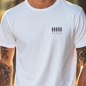 Könnte beinhalten: Weißes T-Shirt mit einer kleinen schwarzen Grafik von fünf Kiefern auf der linken Brust.