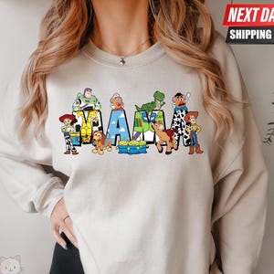 May include: A light gray sweatshirt with a graphic print of characters from the Toy Story franchise spelling out the word "MAMA".
