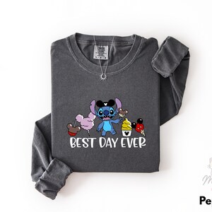 A gray long-sleeved t-shirt with a graphic design featuring a cartoon character and the text "BEST DAY EVER" printed on it.