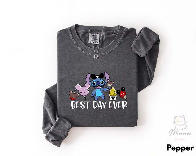 A gray long-sleeved t-shirt with a graphic design featuring a cartoon character and the text "BEST DAY EVER" printed on it.