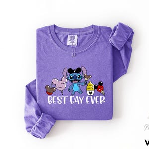 A purple long-sleeved t-shirt with a cartoon character and text printed on it.