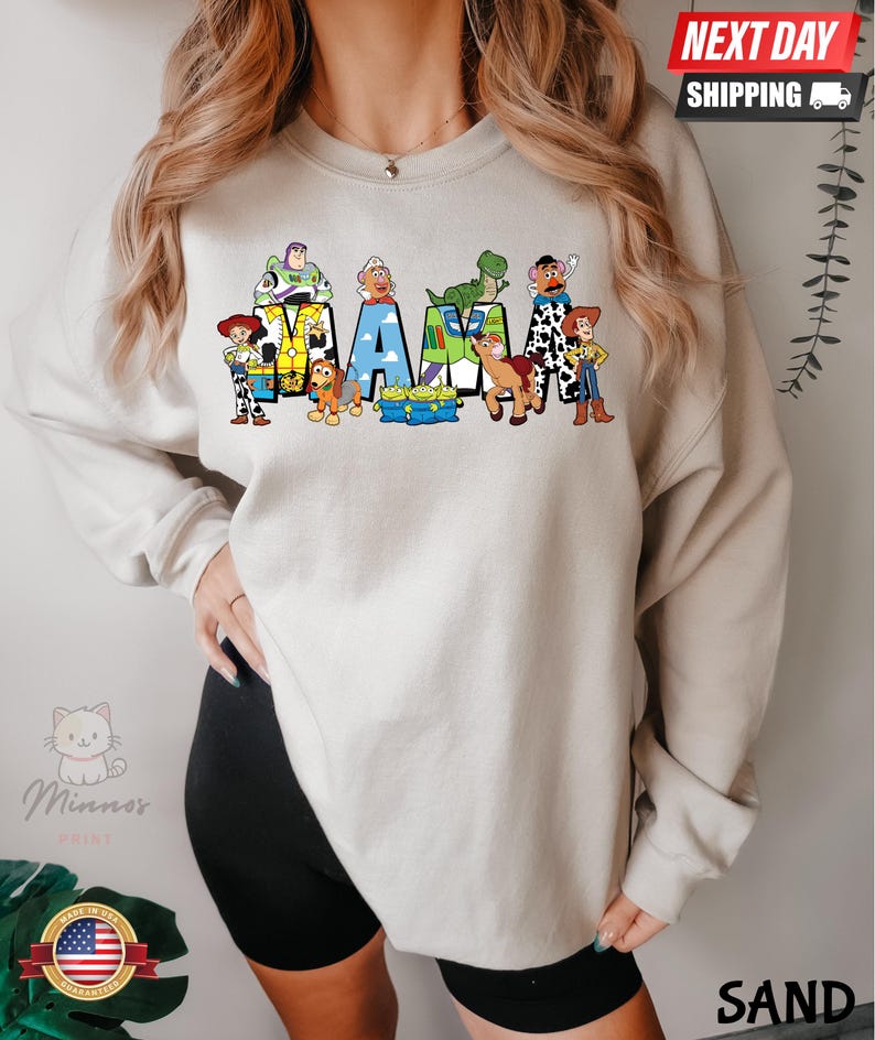 May include: A light gray sweatshirt with a graphic print of characters from the Toy Story franchise spelling out the word "MAMA".